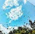 Rain water drops, blue sky, white clouds through window Royalty Free Stock Photo