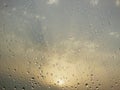 Rain water Drops on glass window on a cloudy day morning with sun glow glare in background hide and seek behind clouds Royalty Free Stock Photo