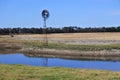 Rain water hole and an old windmill on a farm Royalty Free Stock Photo