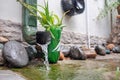 Rain water is pouring from the green draining gutter on the mossy ground Royalty Free Stock Photo