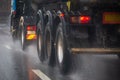 Rain water splash flow from wheels of heavy truck moving fast in daylight city with selective focus. Royalty Free Stock Photo