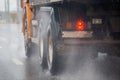 Rain water splash flow from wheels of heavy truck moving fast in daylight city with selective focus. Royalty Free Stock Photo