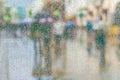 Rain on the window and bokeh city, blurred silhouettes of people, modern urban street. Seasons, weather concept