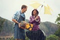 The rain wont stop my barbecue. a couple happily barbecuing in the rain.