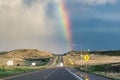 Rainbow above distant highway landscape after summer storm Royalty Free Stock Photo