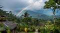 Rainbow arcing over a lush mountain landscape with traditional huts and vibrant greenery