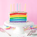 A rainbow birthday cake with unlit candles, ready for a celebration. Royalty Free Stock Photo