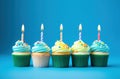 rainbow birthday cupcakes on blue background Royalty Free Stock Photo