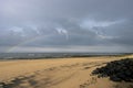 Rainbow on black beach sand on stormy day at Hartlepool Headland, UK