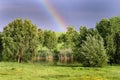 Rainbow over tree lined lake Royalty Free Stock Photo