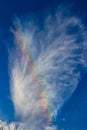 A rainbow cloud against a blue sky, a rare optical phenomenon in the atmosphere