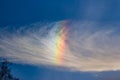 A rainbow cloud against a blue sky, a rare optical phenomenon in the atmosphere