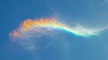 Rainbow cloud in the shape of amber and blue flame, against clear sky,bright blue background Royalty Free Stock Photo