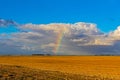 Rainbow and clouds over plowed field Royalty Free Stock Photo