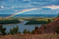 Rainbow with clouds over a river valley Royalty Free Stock Photo