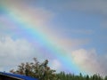 Rainbow in a cloudy sky after rain over the garden Royalty Free Stock Photo