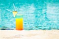 Rainbow cocktail at the edge of a resort pool. Concept of luxur Royalty Free Stock Photo