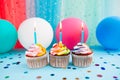 Rainbow color cupcakes with three candles on blue background with colorful air balloons, anniversary card Royalty Free Stock Photo