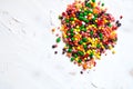 Rainbow colored candy sprinkled on a white background