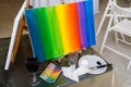 Rainbow colored canvas on the easel with glass of red wine aside Royalty Free Stock Photo