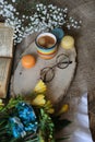 rainbow colored mug of coffee and two cookies and glasses and open book and small flowers in a wood slice on a table with cloth Royalty Free Stock Photo