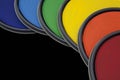 Rainbow colored paint can lids against black background