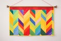 rainbow-colored quilted hanging on a bright wall