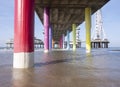 Rainbow colored stone poles under the pier of scheveningen beach the netherlands with sand and waves in the in the sea Royalty Free Stock Photo