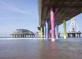 Rainbow colored stone poles under the pier of scheveningen beach the netherlands with sand and waves in the in the sea Royalty Free Stock Photo