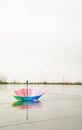 Rainbow colored umbrella lying in puddles on the wet street ground Royalty Free Stock Photo