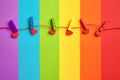 Rainbow colored wooden clothespins with clamped red hearts on lgbt flag background Royalty Free Stock Photo