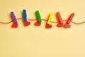 Rainbow colored wooden clothespins with clamped red hearts on yellow background Royalty Free Stock Photo