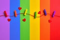 Rainbow colored wooden clothespins and red hearts on lgbt flag background Royalty Free Stock Photo