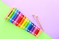 Rainbow colored wooden toy xylophone with two sticks on green and purple background. Top view Royalty Free Stock Photo