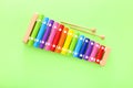 Rainbow colored wooden toy xylophone with two sticks on green background. Top view Royalty Free Stock Photo