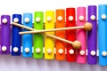 Rainbow colored wooden toy xylophone with two sticks on white background. Royalty Free Stock Photo