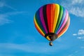 Rainbow colorful hot-air balloon floats on a summer morning with bright blue sky Royalty Free Stock Photo