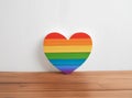 Rainbow colors heart on the centre of wooden table against white wooden wall