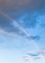 Rainbow between dark clouds in blue evening sky Royalty Free Stock Photo