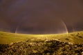 Rainbow with dark sky over a meadow Royalty Free Stock Photo