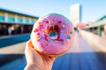 rainbow donut held in hand with street view, life style Authentic living