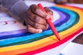 Rainbow drawn with red pencil in a black hand