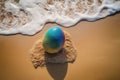 Rainbow Easter egg on a sandy beach Royalty Free Stock Photo