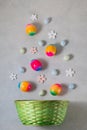 Rainbow Easter eggs with spring flowers falling down into a wicker basket. Easter decoration