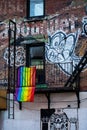 Rainbow flag hanging off of fire escape balcony on side of apartment building Royalty Free Stock Photo