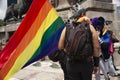Rainbow flag painting Mexico City carried by a man wearing a king`s crown and backpack in the LGBTTI march