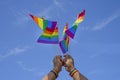 Rainbow flags LGBT community symbol are being waved by a man hands on background clear blue sky Royalty Free Stock Photo