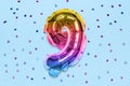 Rainbow foil balloon number, digit nine on a blue background with sequins