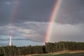 A rainbow forms over a forest after an afternoon thundershower Royalty Free Stock Photo