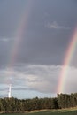 A rainbow forms over a forest after an afternoon thundershower Royalty Free Stock Photo